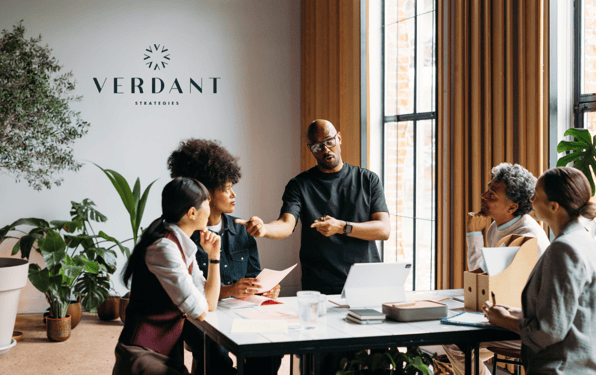 A diverse team meeting at Verdant Strategies, led by a financial advisor presenting strategic insights to cannabis industry professionals around a modern office table.