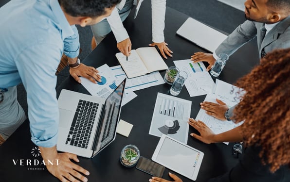 Business team reviewing financial charts, reports, and performance metrics around a conference table during a strategic meeting.
